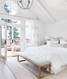 a white bedroom with a large bed and chandelier