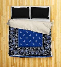 a bed with two pillows on top of it and a blue bandanna around the edge