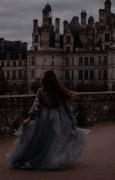 a woman walking across a bridge in front of a large building