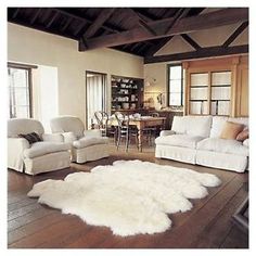 a living room filled with furniture and a white rug on top of a hard wood floor