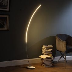 a lamp that is next to a pile of books in a room with a chair