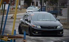 a black car parked on the side of a road next to blue poles and yellow poles