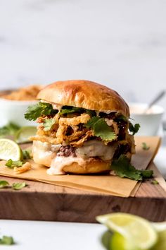 a sandwich with meat, lettuce and cilantro on a cutting board