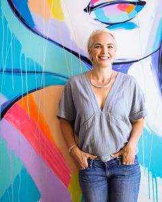 a woman standing in front of a colorful painting