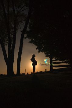 the silhouette of a person standing in front of a tree at night with the sun setting behind them