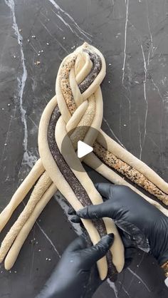 two hands are pulling up a rope made out of sand and other items on a table