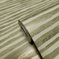 a roll of metallic foil on top of a striped wallpaper with white and grey stripes