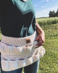 a woman wearing a crochet wrap around her waist holding an egg in it