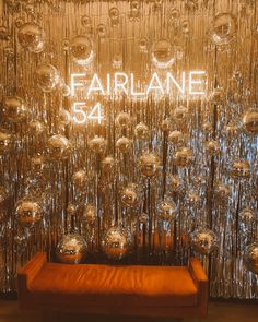 an orange bench sitting in front of a wall covered with shiny balls