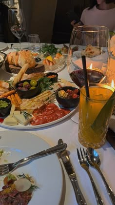 a table full of food and silverware with wine glasses on the table in front of it