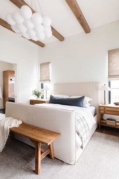 a bedroom with a bed, bench and windows in the room that has wood beams on the ceiling