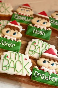 decorated cookies are arranged on a wooden board with name tags in the shape of children's faces