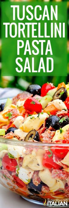 a salad with tomatoes, olives, and other vegetables in a glass bowl on a table