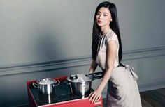 a woman standing next to a red stove with pots on the burners in it