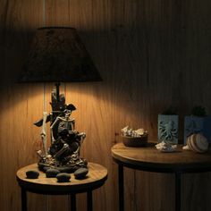 a table with a lamp on it next to a wooden wall and two small tables