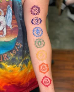 a person with a tattoo on their arm that has seven chakras in different colors