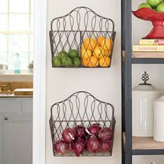 the magazine holder has fruit in it and is hanging on the wall next to shelves