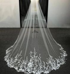 a white wedding veil with flowers on the bottom is shown in front of a doorway