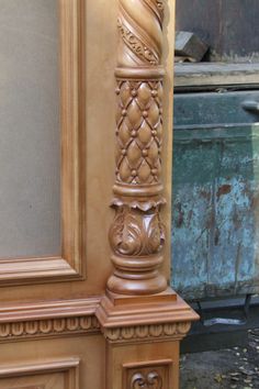 a tall wooden pillar sitting in front of a window next to a wall with an ornate design on it