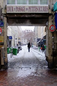 a person walking under an overpass on a snowy day in the middle of town