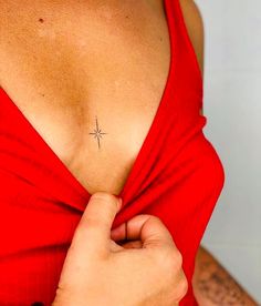 a woman wearing a red dress with a small cross tattoo on her left side chest