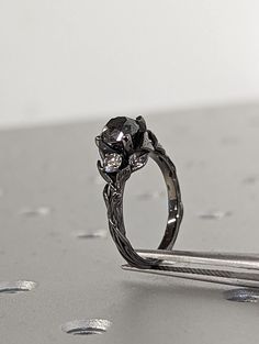 a diamond ring sitting on top of a piece of metal with drops of water around it