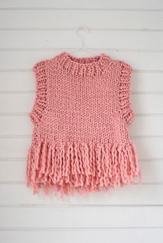 a pink sweater hanging on a white wall