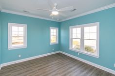 an empty room with blue walls and white trim on the windows, wood flooring