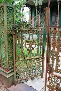 an old iron gate in front of a house with green paint on the walls and doors