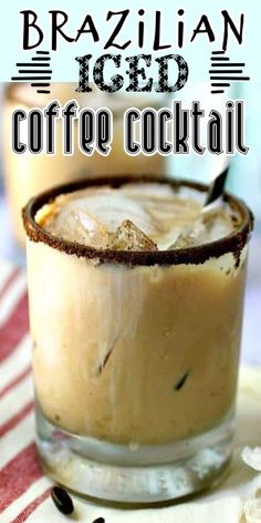 a close up of a drink in a glass on a table with coffee beans around it