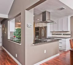 an empty kitchen with wood floors and white cabinets