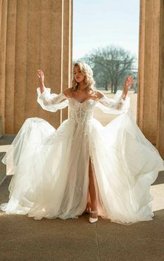 a woman in a white wedding dress posing for the camera with her arms spread out