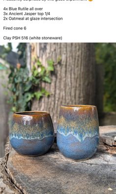 two blue cups sitting on top of a wooden table next to a green tree trunk