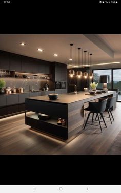 an image of a modern kitchen setting with lights on the ceiling and dark wood flooring