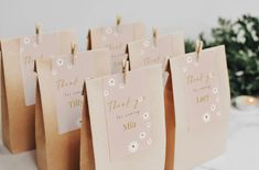 small pink bags with white flowers and thank you for being married on them are sitting next to a christmas tree