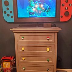 a tv that is on top of a dresser in front of a wall with video game controllers