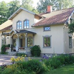 a large white house with lots of windows and flowers in front of the house on a sunny day