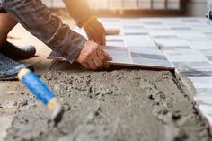 a man laying tile on the ground