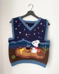 a knitted sweater with a dog on it hanging from a hanger in front of a white wall