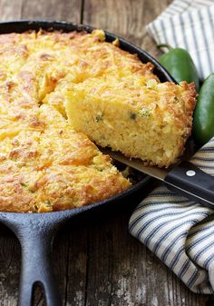 a skillet filled with cornbread on top of a table next to a knife