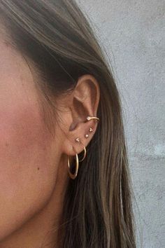 a close up of a person with ear piercings on their ears and wearing earrings