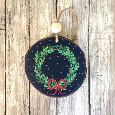 a blue christmas ornament hanging from a string on a wooden surface with a red bow