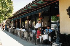 people are sitting at tables in front of a restaurant