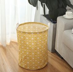 a yellow basket sitting on top of a wooden floor next to a white couch and potted plant