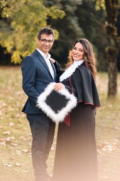 a man and woman dressed up in formal wear posing for a photo with trees in the background