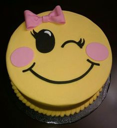 a smiley face cake with a pink bow on top