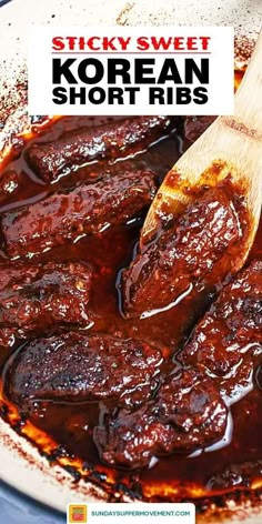 a wooden spoon in a pot filled with sticky sweet korean short ribs, topped with bbq sauce