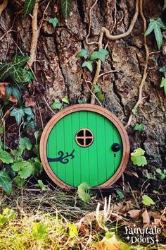 an image of a green door in the ground near a tree trunk with ivy growing around it