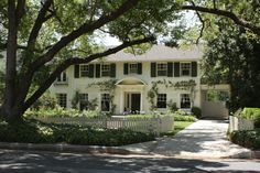 a white house surrounded by trees and bushes