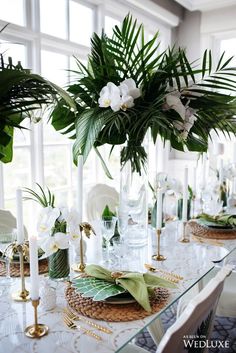 the table is set with white flowers and greenery